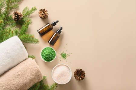 Christmas Spa wellness concept with cosmetic aroma oil, pine cones on beige background.の写真素材