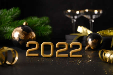 New Year 2022 festive composition with number of year , gift, baubles, gift and wine glasses.