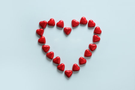Romantic chocolate sweets as heart in red foil and text on wooden blocks - Love in white plate.の写真素材