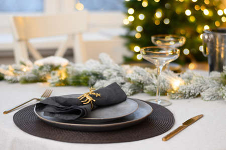 Christmas festive table setting, gold decorate and champagne. Family holiday dinner or New Year...