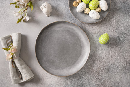 Easter festive table setting with gray plate, spring flowers and green colorful eggs.の写真素材