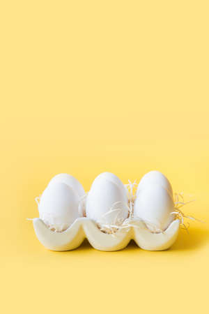 Organic white chicken eggs in porcelain decorative box on yellow.の写真素材