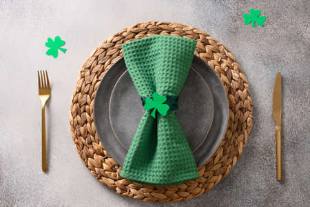St Patricks Day party table setting with green decor on gray background.