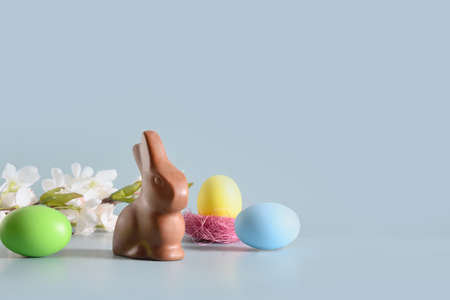 Easter pink egg and chocolate bunny in spring composition on blue.