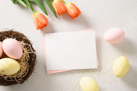 Easter greeting card with colorful eggs, decorative nest on white background. View from above. Greeting card with copy space.の写真素材