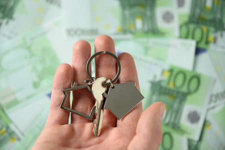 Keys from a new house in hand on the background of euro currency.