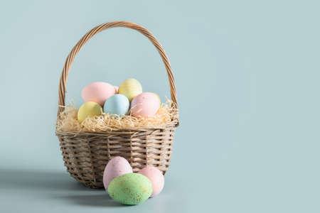 Easter wicker basket with pastel colorful eggs for festive holiday.の写真素材