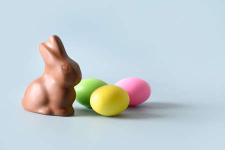 Easter chocolate bunny and colorful eggs on blue.