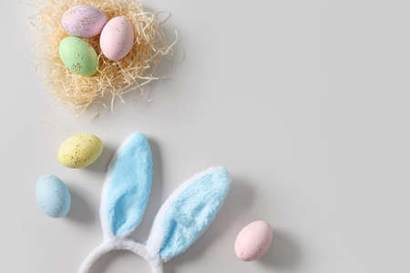 Easter bunny ears, nest and pastel colorful eggs on gray background.の写真素材