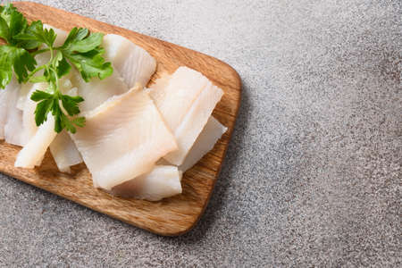 Delicacy fish smoked halibut served with parsley for eating on wooden cutting board. Close up.の写真素材