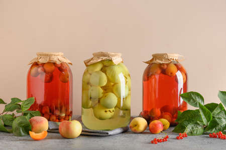 Three canned apple and cherry compote in large glass jars on gray table.