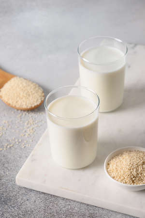White Sesame milk in two glasses on gray background. Close up. Vegan non dairy alternative plant based milk. Vertical.の写真素材