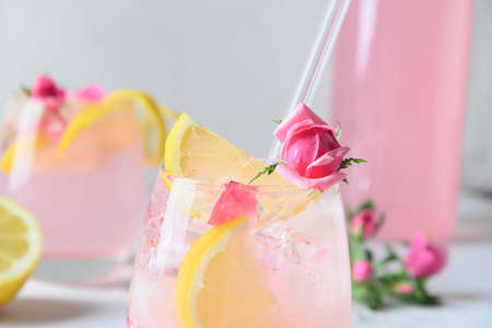 Pink rose cocktails or lemonade with rose flowers and lemon on white sunny background. Close up....