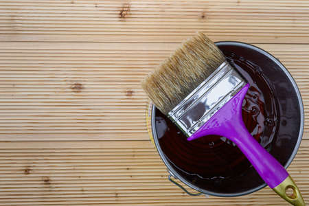 Painting new wooden boards for patio by special protective oil. A jar of protective waterproof oil with brush for covering larch floors from bad weather. View from above.の写真素材
