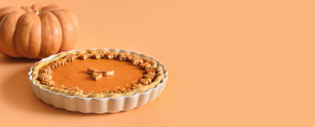 American Pumpkin Pie for autumn holiday on orange background with copy space. Close up. Happy Thanksgiving Day. Banner.の写真素材