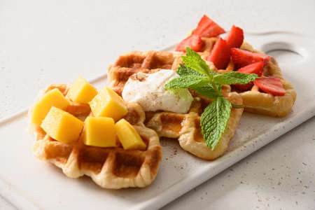 Crispy croffles with different fruits topping of strawberries, mango on white background. Close up.の写真素材