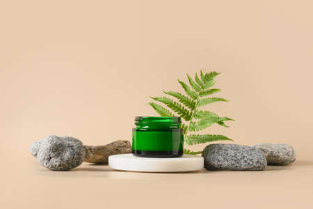 Podium for cosmetic products in modern composition with tropical fern leaves and stones on beige background.の写真素材