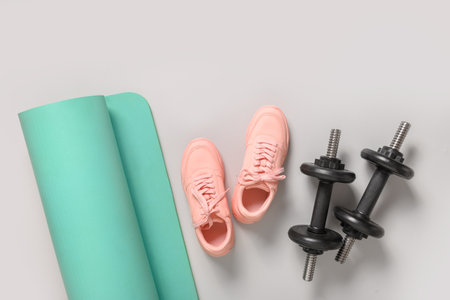 Sport and fitness equipment, female pink shoes, yoga mat on grey background. Copy space. View from above.の写真素材