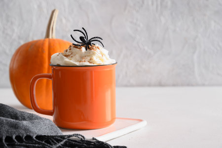 Halloween latte coffee with whipped cream decorated spiders and pumpkin on white background. Copy space. Close up.の写真素材