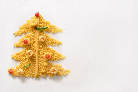 Alternative Christmas tree of different shape Italian pasta with tomatoes, basil on white background. Xmas greeting card. View from above. Food holiday concept.の写真素材