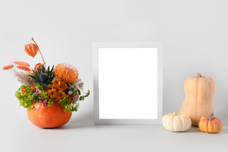 Autumn mockup with flowers bouquet in pumpkin, decor elements and white frame on white background. Copy space. Fall template.の写真素材