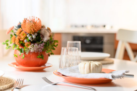 Thanksgiving day table setting decoration beautiful centerpieces with orange flowers in pumpkins on white table in home kitchen interior. Close up.の写真素材