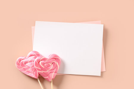 Valentines day greeting card with empty blank and two pink lollipops sweets as heart on pink background. View from above. Minimal flat lay. Copy space.の写真素材