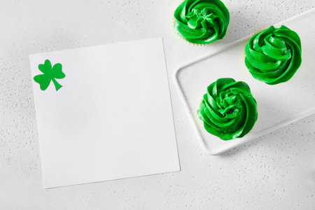 Patricks Day homemade cupcake with green whipped cream and blank with shamrock on white background. View from above. Copy space.の写真素材