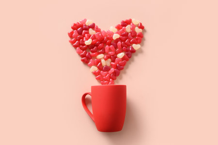 Valentines day greeting card with concept of red cup and small sweets in shape of big heart on pink background. View from above.の写真素材