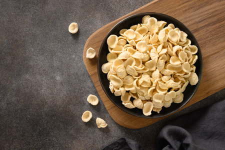 Orecchiette pasta made from whole wheat flour on dark brown background. Copy space. Top view.の写真素材