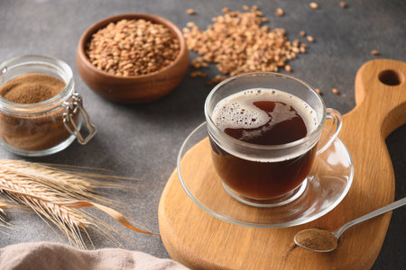 Barley coffee in glass cup, beans and ears of barley on brown background. Natural caffeine free organic coffee alternative. Beverage made of healthy blend of roasted barley. Close up. Copy space.の写真素材