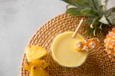 Pineapple lassie or smoothie on gray background. Traditional Asian beverage of pineapple, yogurt and...