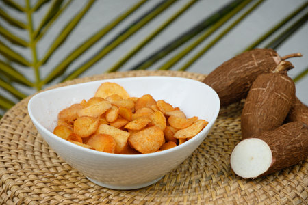 Organic manioca or cassava chips in bowl and tapioca tuber. Indonesia popular hot spicy snacks. Close up.の写真素材