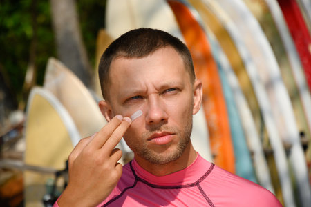 Man surfer applies protective zinc on his face. Preparing to surf. Best protection from active sun...