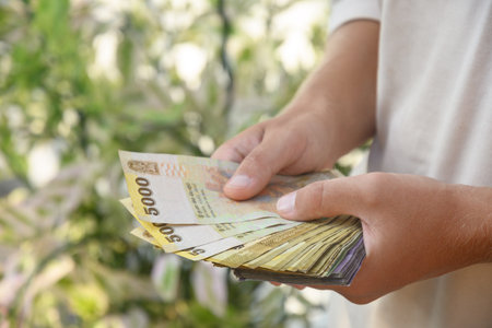 Hand of man holding Sri Lanka rupees banknotes of different denominations. Close up. Outdoors.の写真素材