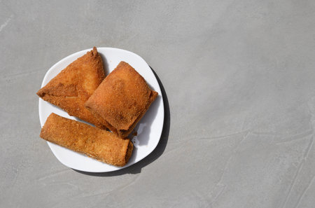 Sri Lankan Chinese Rolls different shape, short eats on gray background. Pan rolls. Authentic street food, vegetable and fish rolls deep fried. Top view, copy space.の写真素材