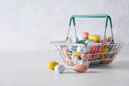 Easter composition with colorful chocolate eggs in shopping cart on white background. Copy space....