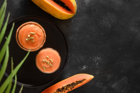 Two Asian traditional Pineapple lassi or smoothie in glasses on black background. Freshness cold beverage made of yogurt, water, spices, fruits and ice. Popular beverage in India and Sri lanka. Top view. Copy space.の写真素材