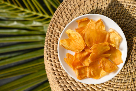 Jackfruit chips in white plate on tropical background with leaf. Vegan sugar free fruits chips for with antioxidant, vitamin from Ceylon. Top view. Local food tasty snacks.の写真素材