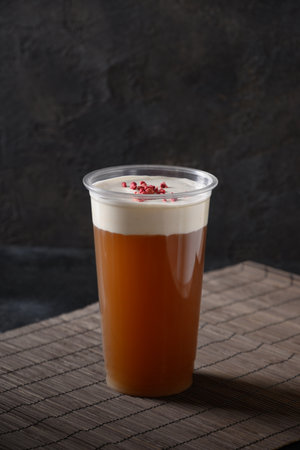 Chinese cheese tea in plastic cup with whipped cream cheese topped berries on black background. Vertical format. Asian cuisine and local food.の写真素材