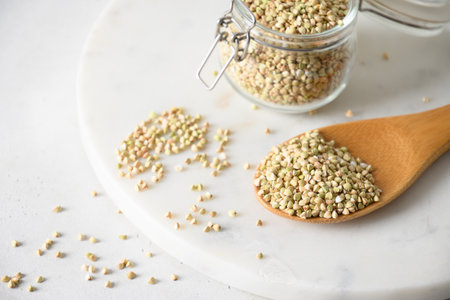 Organic raw green buckwheat in wooden spoon on white background. Close up. Copy space.の写真素材