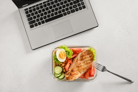 Lunchbox with healthy salad and glass of water in office on gray table. Concept healthy eating on work. Top view with copy space.の写真素材
