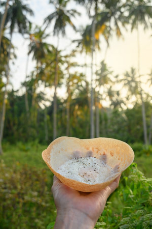 Sri lankan street food egg hopper in womans hand. Close up. Local food. Outdoors. bittara appa.の写真素材