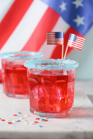 Patriotic red pomegranate margarita cocktail and USA flag as background. Vertical format. Close up. Festive beverages for July 4th.の写真素材