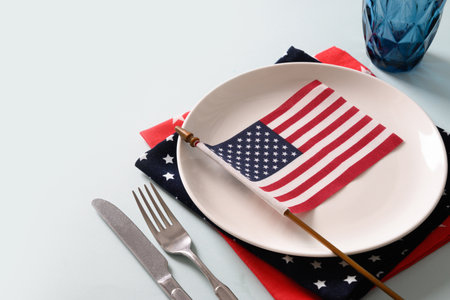 Patriotic table setting with USA flag and decoration in national flag colors on white blue background. Independence Day. Happy Memorial Day. Close up.の写真素材