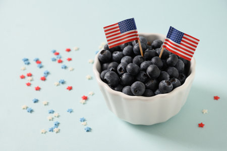 Blueberry decorated two US flags in white bowl on blue background. Concept preparations for Patriotic Independence Day 4th of july. Close up. Copy space.の写真素材