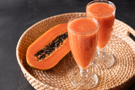 Freshness Papaya lassi, smoothie served in asian traditional tray on black background. Ayurvedic beverage in India and Sri lanka. Close up. Copy space.の写真素材