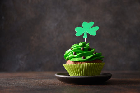 St. Patricks Day cupcake with green whipped cream decorated clover on dark brown background. Copy space. Close up. Festive food.の写真素材