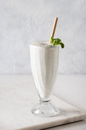 Indian Salty lassi with mint leaves and kala namak on white background. Vertical format. Traditional healthy freshness lassi made of yogurt, water, spices and ice.の写真素材