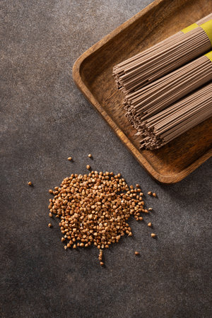 Uncooked buckwheat noodles soba on dark gray background. View from above. Space for text. Healthy vegan diet.の写真素材